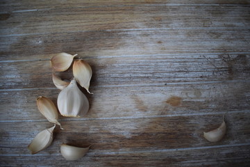 Uncleaned garlic heads with roots and stems on a wooden painted light background. Copy space.