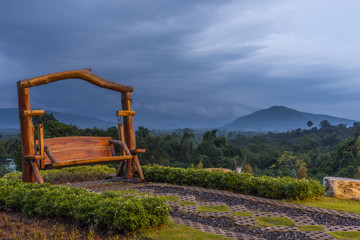 Fototapeta na wymiar wooden porch swing in the mountain resort at sunset in pouring rain