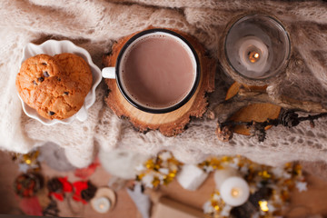 Obraz na płótnie Canvas Cocoa with Cozy winter home background, cup of hot cacao with american cookies, warm knitted sweater on vholiday decoration blur background, vintage tone, top vew, copy space. Lifestyle rustic nordic