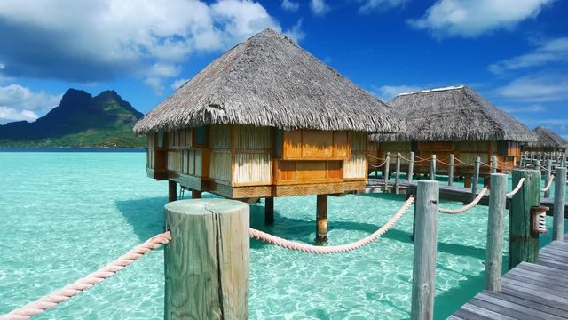 Luxury overwater villas on blue lagoon, white sandy beach and Otemanu mountain at Bora Bora island, Tahiti, French Polynesia

