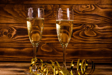 Two wineglasses with champagne and golden ribbon on wooden table