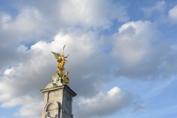 Fototapeta na wymiar Golden statue built on the tower, blue sky and white clouds