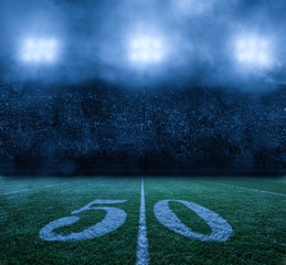 American Football Stadium at night 50 yard line. Stadium lights on a misty clouded night. Nobody in...