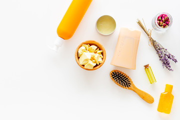Cosmetics for hair care with jojoba, argan or coconut oil. Bottles and pieces of oil on white background top view copy space