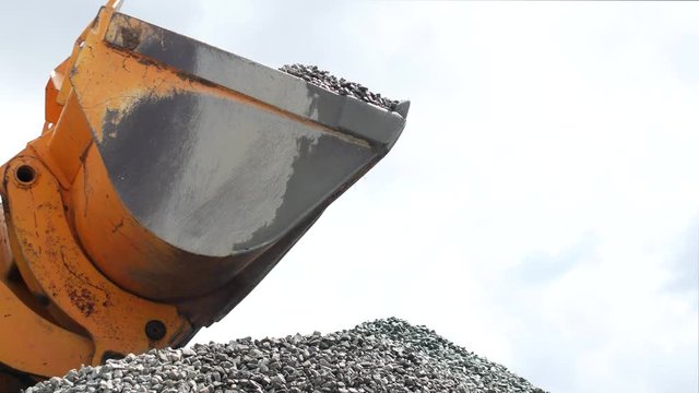 Large loader pours rubble from bucket, close-up, empty dipper