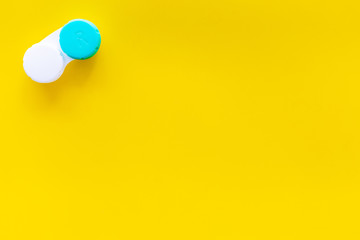 Improve vision concept. Contact lenses in container on yellow background top view copy space