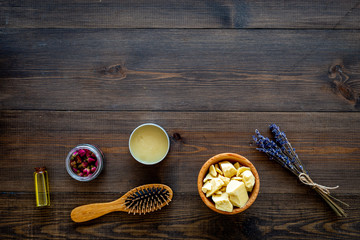 Natural oil for hair. Jojoba, argan, coconut oil near bunch of lavender and hairbrush on dark wooden background top view copy space