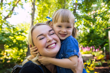 Fototapeta premium Cute blonde woman and her daughter have fun in the park