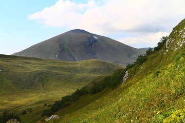 Fototapeta premium wonderful mountain slope natural landscape photo with green meadow on blue sky background