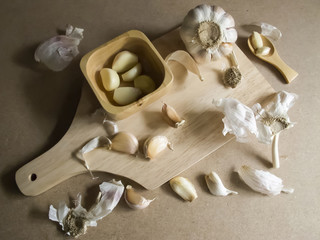 Fresh Garlic Cloves and Garlic Bulb on chopping board / MDF wooden plate board texture background