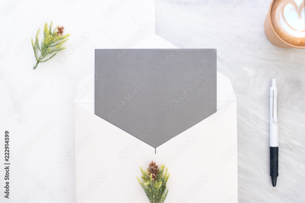 Poster Top view of blank grey card in white envelop with coffee and pine leaf on two layer step of marble table top.Mock up template for display of design.modern business items.