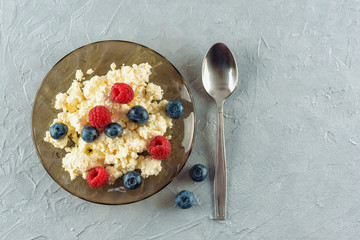 Cottage cheese with fresh raspberries and blueberries in a plate for a healthy breakfast with ripe berries. A natural healthy product.