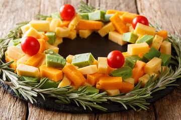 delicious Christmas set of pesto cheese, cheddar, mimolette with tomatoes and rosemary close-up on the table. horizontal