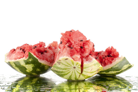 Watermelon broken pieces on white mirror background in water drops isolated close up