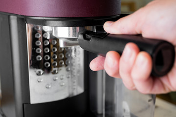 Woman placing a group head in a coffee machine to make a morning espresso. Breakfast and home equipment concept.