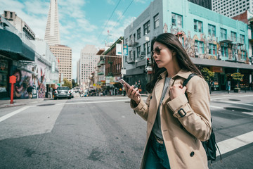woman using cell phone while crossing the road