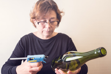 Woman decorating a bottle from wine with an ecological twine. Rustic style, handmade craft. Gift for christmas and other celebrations. Crafting process. Selective focus