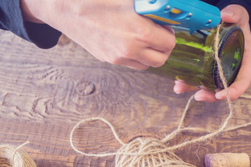 Woman decorating a bottle from wine with an ecological twine. Rustic style, handmade craft. Gift for christmas and other celebrations. Crafting process. Selective focus