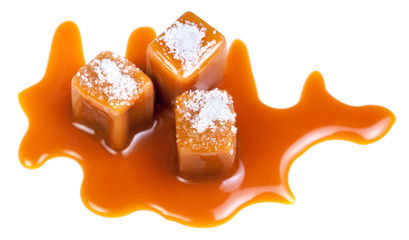Caramel candies with caramel sauce and salt crystals on the top  isolated on a white background