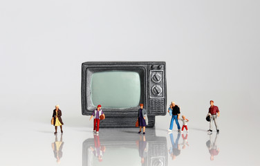 Miniature people walking in front of miniature television.