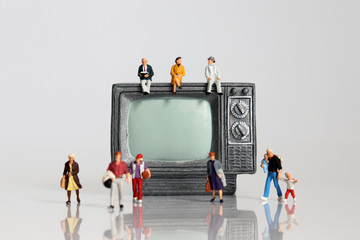 Miniature diverse people with miniature television.