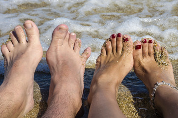 A couple's feet on the background of the sea.View of a couple's feet on the sand beach. Close-up of feet of a pair of lovers.One man and one girl feel free on the beach