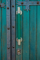 Fototapeta na wymiar An old green closed door with large door handles and a keyhole