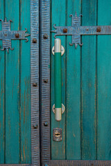 An old green closed door with large door handles and a keyhole