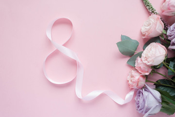 Frame of purple and pink roses, white Lisianthus and different flowers on pink background.