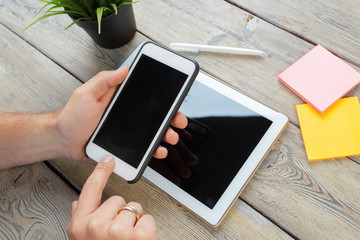 hands of a man holding tablet device over a wooden workspace table
