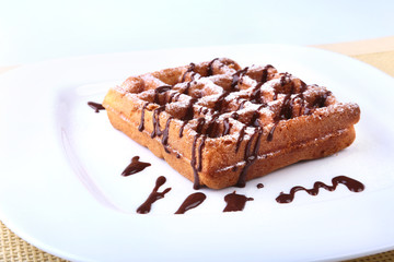 White plate with homemade belgian waffles with Sifting sugar powder over black background.