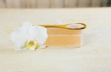 Bar of orange Himalayan crystal Salt Soap on wooden background with wooden spoon with pink orange Himalayan crystal Salt grains in. Body care concept.