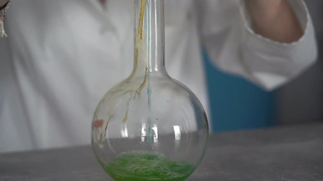 Woman scientist mixing chemicals in flask
