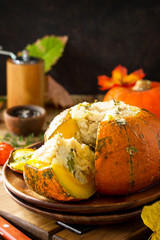 Thanksgiving Turkey dinner. Baked pumpkin stuffed with Turkey, rice and vegetables on rustic background. The concept of food on thanksgiving. Copy space.