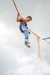 happy young boy jumping on bungee trampoline