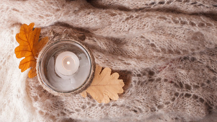 Cozy wool winter autumn fall accessory. Warm pleid and candle on a wooden table/ Authentic Tranquil Atmosphere. Kinfolk Hygge Slow Living Style. Top view