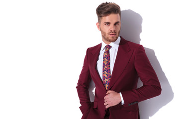 portrait of a handsome elegant man buttoning his burgundy suit