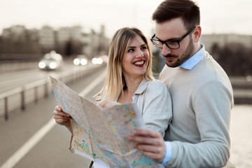 Smiling couple in love traveling with a map outdoors
