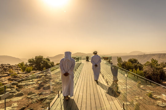 Two mans dressing with arab white clothes in a hotel in Oman. Orange predominance in the picture, feeling of desert, dry place, no clouds