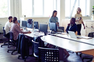 Just working day. Young modern colleagues in smart casual wear working together while spending time in the creative office.