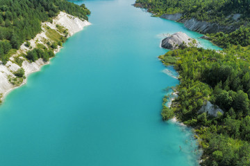 Abandoned mountain quarry. The mine workings are filled with water of a deep blue color. Aerial view