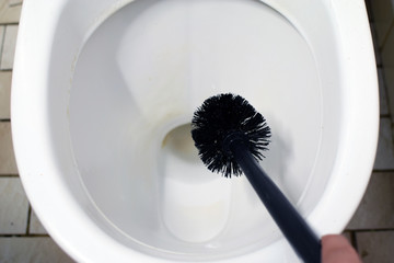 Cleaning toilet bowl with scrub brush