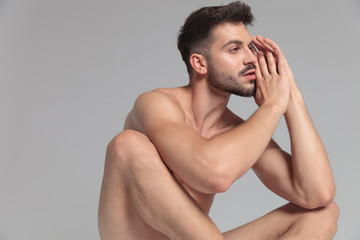 young fit naked man looks away while sitting