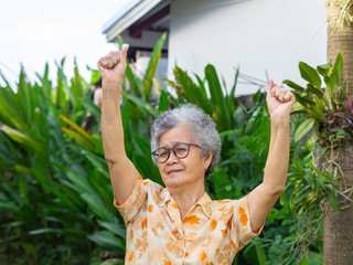 Portrait of happy senior woman raising both arms upwards.