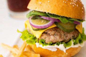 Big single cheeseburger with french fries isolated on white background. Copy space.