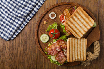 Toasted sandwich with bacon, tomato, cucumber and lettuce.