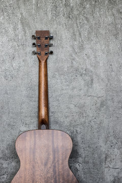 back of acoustic guitar lean against cement wall