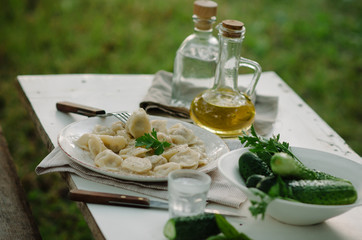 Homemade Meat Dumplings - russian pelmeni with fresh parsley on plate. Dinner outside in the garden