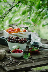 Mix of fresh berries and fruit in vintage wooden box on rustic wooden background. Raw healthy food. Assorted summer berries and fruit.