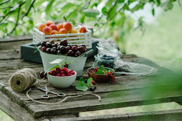 Mix of fresh berries and fruit in vintage wooden box on rustic wooden background. Raw healthy food. Assorted summer berries and fruit.